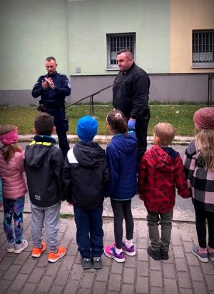 Policjanci na placu komendy rozmawiają z dziećmi o bezpieczeństwie