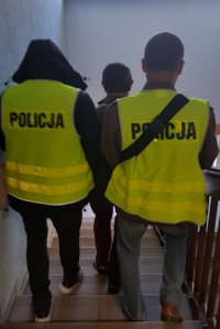 Policjanci prowadzą zatrzymanego po schodach