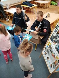 Policjanci wręczają dzieciom książeczki