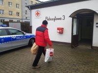 Mężczyzna niesie paczki do siedziby Polskiego Czerwonego Krzyża