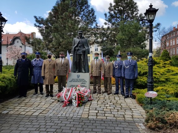 Uczestnicy uroczystości stoją obok pomnika Józefa Piłsudskiego