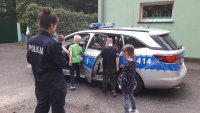 Dzieci w obecności policjantki siedzą w policyjnym samochodzie