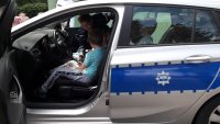 Policjantka tłumaczy dzieciom działanie różnych funkcji samochodu policyjnego
