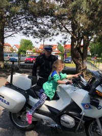 Dziewczynka siedzi na motocyklu w obecności policjanta