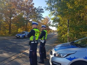 Umundurowani policjanci nadzorują dbają o bezpieczeństwo na drogach w rejonie zmantarza