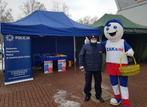 Policjant stoi obok maskotki ZAK