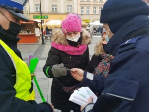 Policjanci podczas świątecznego jarmarku wręczają mieszkańcom opaski odblaskowe i zawieszki do prezentów