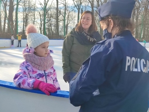 Policjantka rozmawia z dziećmi i wręcza im upominki