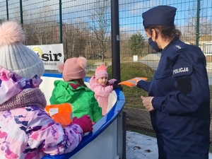 Policjantka rozmawia z dziećmi i wręcza im upominki