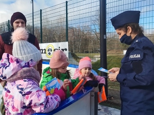 Policjantka rozmawia z dziećmi i wręcza im upominki