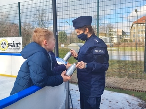 Policjantka rozmawia z dziećmi i wręcza im upominki