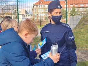 Policjantka rozmawia z dziećmi i wręcza im upominki