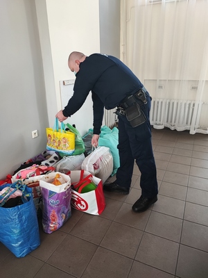 policjanci noszą rzeczy zgromadzone dla uchodźców