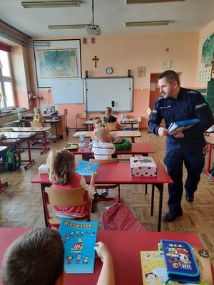 policjant wręcza uczniowi książeczkę