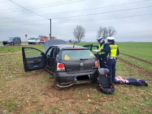 na zdjęciu rozbity samochód i dwoje policjantów