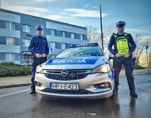 na zdjęciu dwóch policjantów ruchu drogowego stoi przy radiowozie
