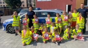 policjanci z uczniami stoją przed radiowozem