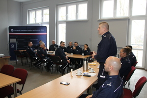 Policjanci i przedstawiciele służb siedzą na sali konferencyjnej przy stołach