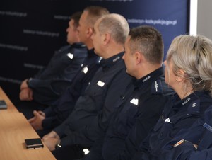 Policjanci i przedstawiciele służb siedzą na sali konferencyjnej przy stołach