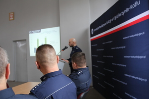 Policjanci i przedstawiciele służb siedzą na sali konferencyjnej przy stołach