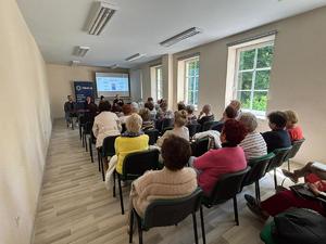 grafika przedstawia policjantów oraz uczestników debaty w sali konferencyjnej