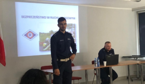 zdjęcie kolorowe- na nim  funkcjonariusz policji przedstawiający prezentacje.