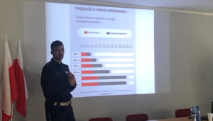 zdjęcie kolorowe- na nim  funkcjonariusz policji przedstawiający prezentacje.