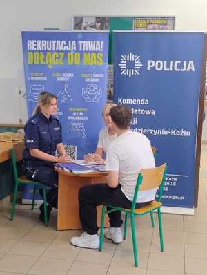 zdjęcie kolorowe - na nim funkcjonariusz z pracownikiem cywilnym rozmawiają z mężczyzną