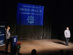 zdjęcie kolorowe - przedstawiające sylwetki funkcjonariuszy na scenie