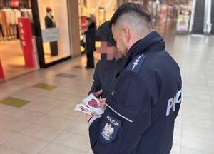 policjanci z uczniami rozdający ulotki w galerii handlowej