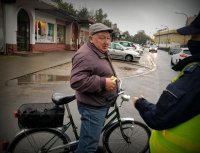 Policjantka wręcza na ulicy rowerzyście odblask