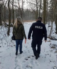 Policjant ze streetworkerem idą przez teren zalesiony