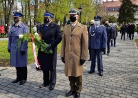 Delegacja mundurowych stoi z wiązanką kwiatów