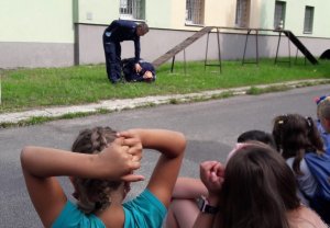 Policjanci prezentują pozycję jaką należy przybrać w przypadku ataku psa