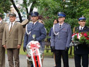 delegacje stoją pod pomnikiem z kwiatami